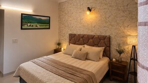 Un dormitorio con cama, mesita de noche, lámpara de pared, ventilador de techo y un cuadro en la pared.