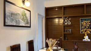Un comedor con una mesa dispuesta para cuatro personas, un cuadro enmarcado en la pared y una estatua de Buda en una estantería.