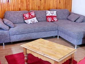 A grey sectional sofa with two decorative pillows against a wooden wall. In front is a wooden coffee table. - Chalet La Brise by Interhome (Tignes)