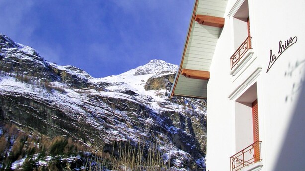 A building with a balcony and a mountain in the background.