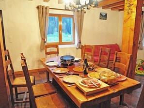 Ein Esszimmer mit Holztisch, gedeckten Plätzen, Stühlen und einem Fenster mit Vorhängen.