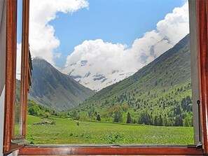 Eine Berglandschaft durch ein Fenster mit Holzrahmen.