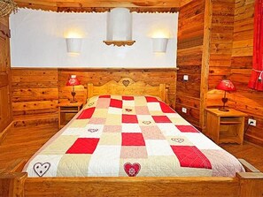 A wooden room with a bed, two bedside lamps, and a wall-mounted light fixture. - Chalet Le Haut by Interhome (Champagny-en-Vanoise)