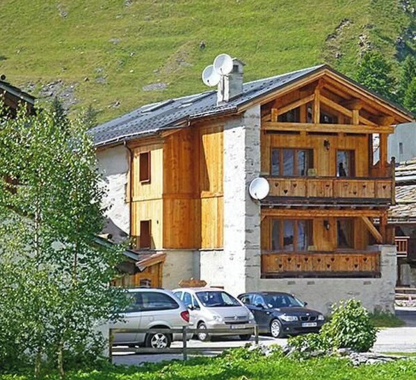 A two-story wooden building with a balcony, a satellite dish, and parked cars in front. - Chalet Le Haut by Interhome (Champagny-en-Vanoise)