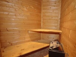A wooden sauna with a bench and a small trash bin. - Champagny CPV01 by Interhome (Champagny-en-Vanoise)