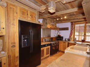 Eine Küche mit Holzschränken, einem schwarzen Kühlschrank, einem Herd und einer Spüle.