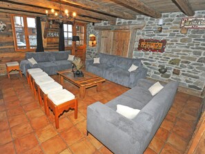 Ein rustikaler Innenraum mit Steinwand, Holzmöbeln und einer Kristallleuchtre.