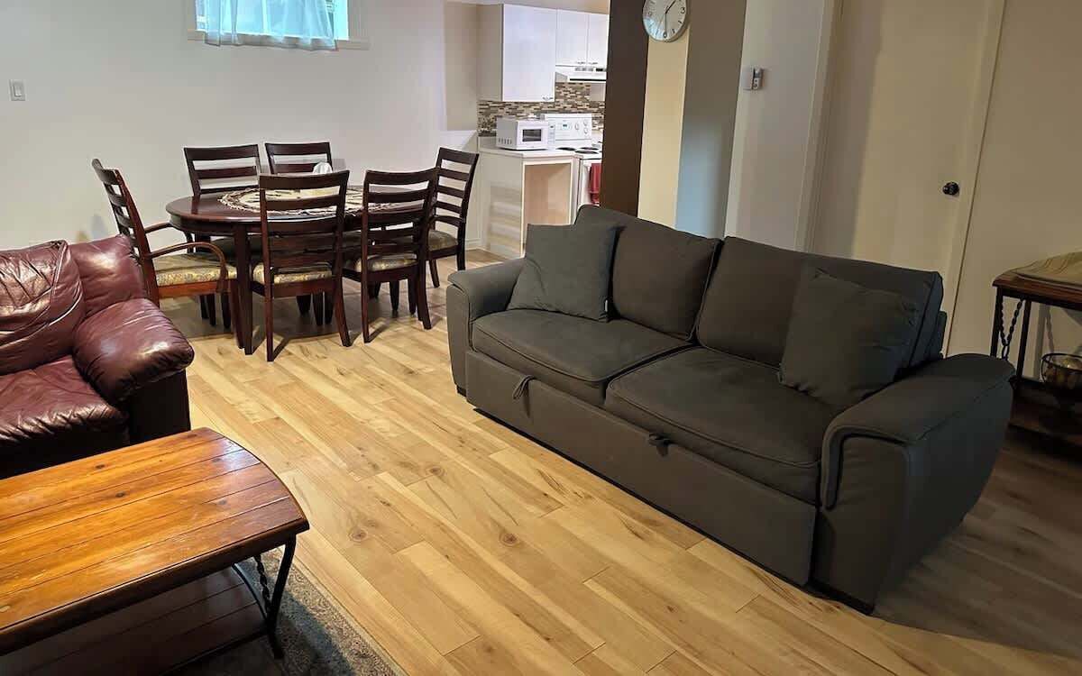 A living room with a sofa, a wooden coffee table, and a dining table with chairs.