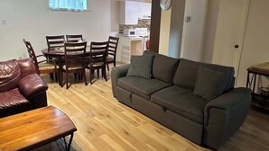 Ein Wohnzimmer mit einer Couch, einem Holztisch und einem Esstisch mit Stühlen.