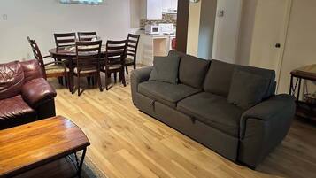 A living room with a sofa, a wooden coffee table, and a dining table with chairs.