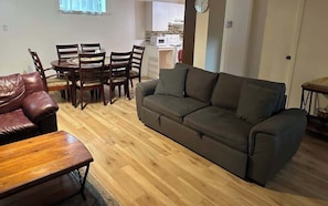 Ein Wohnzimmer mit einer Couch, einem Holztisch und einem Esstisch mit Stühlen.