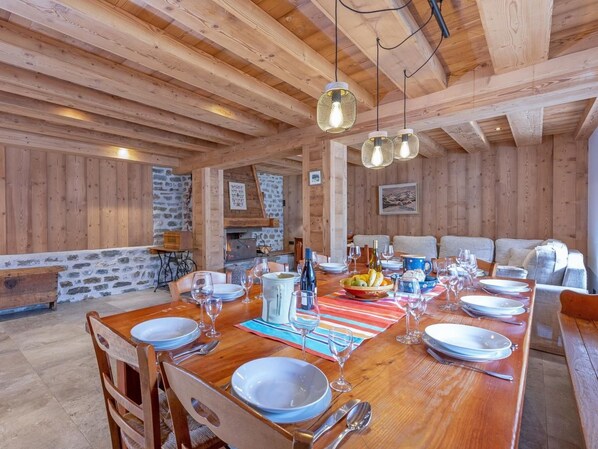A wooden dining area with a long table set for a meal, surrounded by stone walls and wooden beams. - Chalet de Claude by Interhome (Peisey-Nancroix)