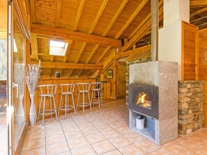 A wooden interior with a stone fireplace, a bar area with stools, and a skylight. - Chalet Ulysse by Interhome (Peisey-Nancroix)