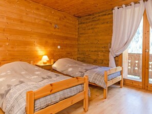 Eine Hütte mit zwei Holzbetten, einem Nachttisch mit Lampe und einem Fenster mit Vorhängen.