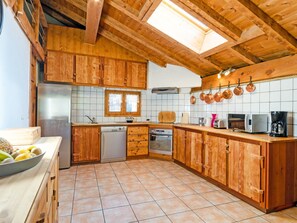 Uma cozinha com armários de madeira, uma geladeira de aço inoxidável, uma lava-louças, um forno e um micro-ondas.
