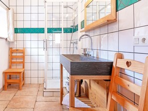 A bathroom with a shower, a sink, and a wooden chair. - Chalet Honore by Interhome (Peisey-Nancroix)