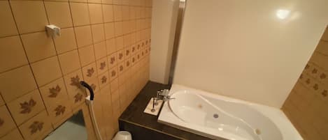 A bathroom with a bathtub, toilet, and a mirror.