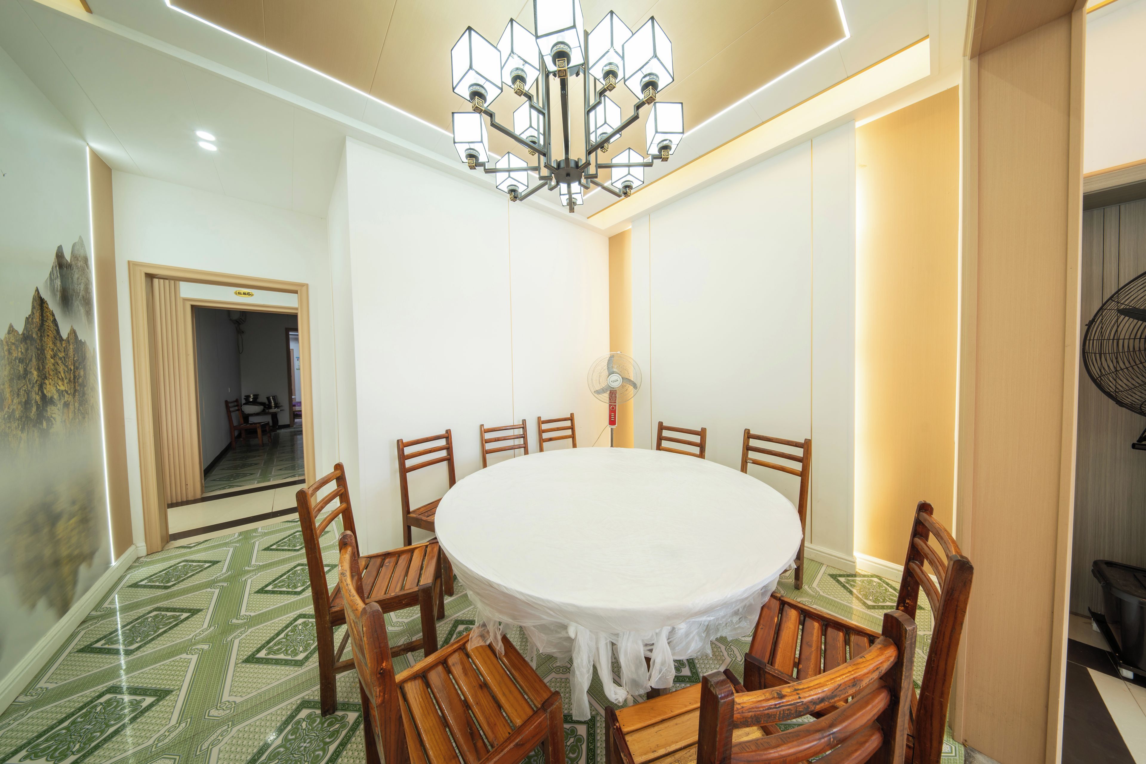 Uma sala de jantar com mesa redonda, cadeiras de madeira, um candelabro e piso estampado.