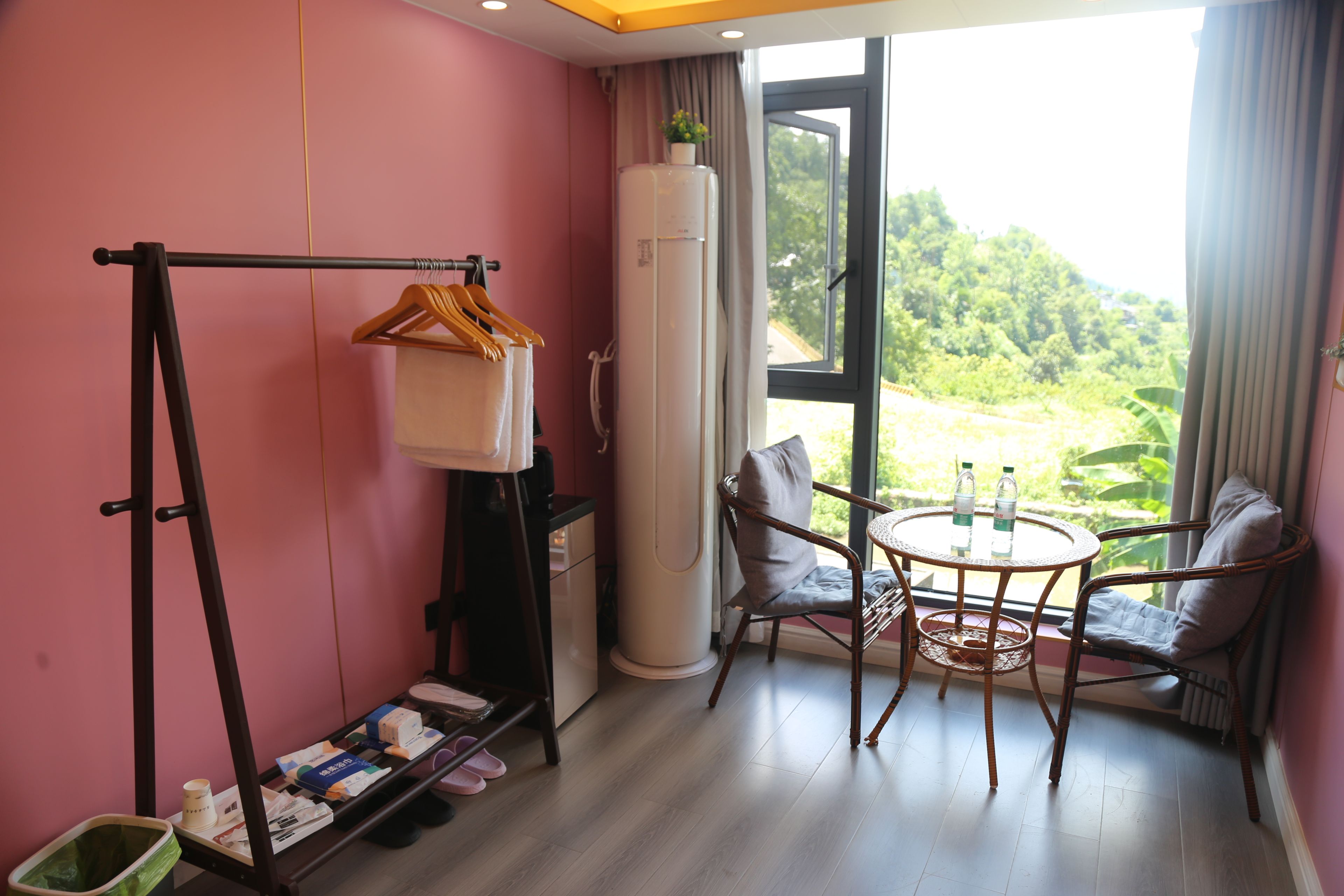 Una habitación con cama, una mesa con sillas, una ventana con vistas a la vegetación y un tendedero.
