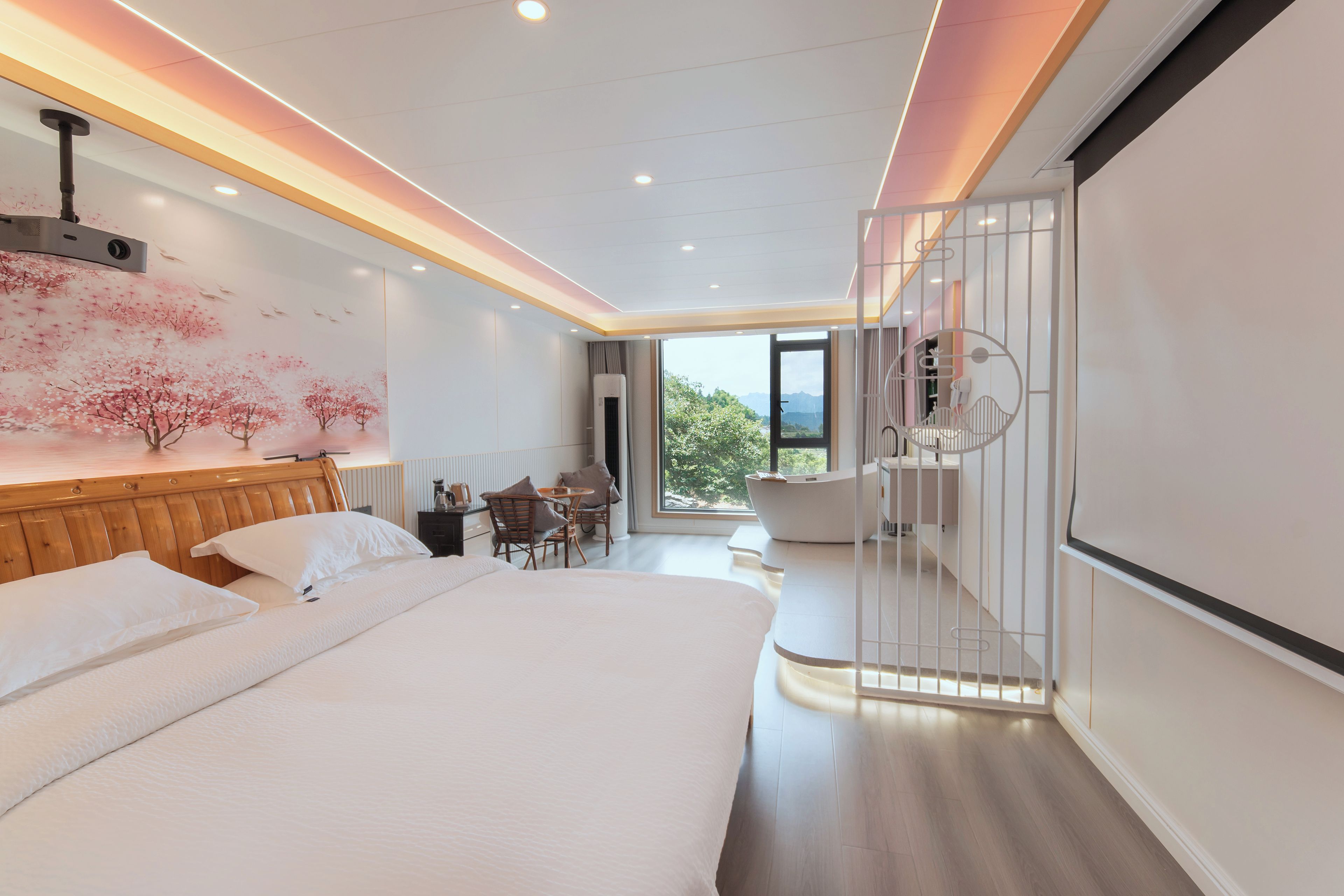 A modern hotel room with a large bed, a dining area, and a view of the outdoors.