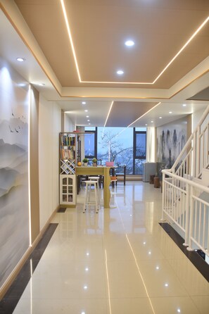 A modern interior with a kitchen area, dining table, and a staircase. - Xishan Yangjiajie Scenic Lodge (Zhangjiajie)