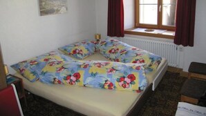 A bedroom with a bed, a window with curtains, a radiator, and a painting on the wall. - Chasa Suzöl, (Lavin) by Interhome (Lavin)