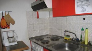 A compact kitchen with a stove, sink, and a coffee maker. - Chasa Suzöl, (Lavin) by Interhome (Lavin)