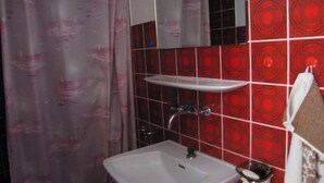 A bathroom with a white sink, a mirror, a shower curtain, and red patterned tiles. - Chasa Suzöl, (Lavin) by Interhome (Lavin)
