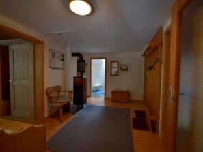 A hallway with a wooden door, a chair, a small table, and a bench. - Via Paclera 23, (Sta. Maria - Santa Maria Val Müstair) by Interhome (Sta. Maria GR)