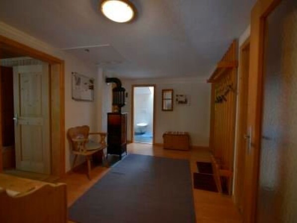 A hallway with a wooden door, a chair, a small table, and a bench. - Via Paclera 23, (Sta. Maria - Santa Maria Val Müstair) by Interhome (Sta. Maria GR)