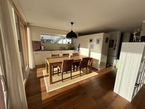 Eine moderne Küche mit Essbereich, Holzboden und einem großen Fenster.