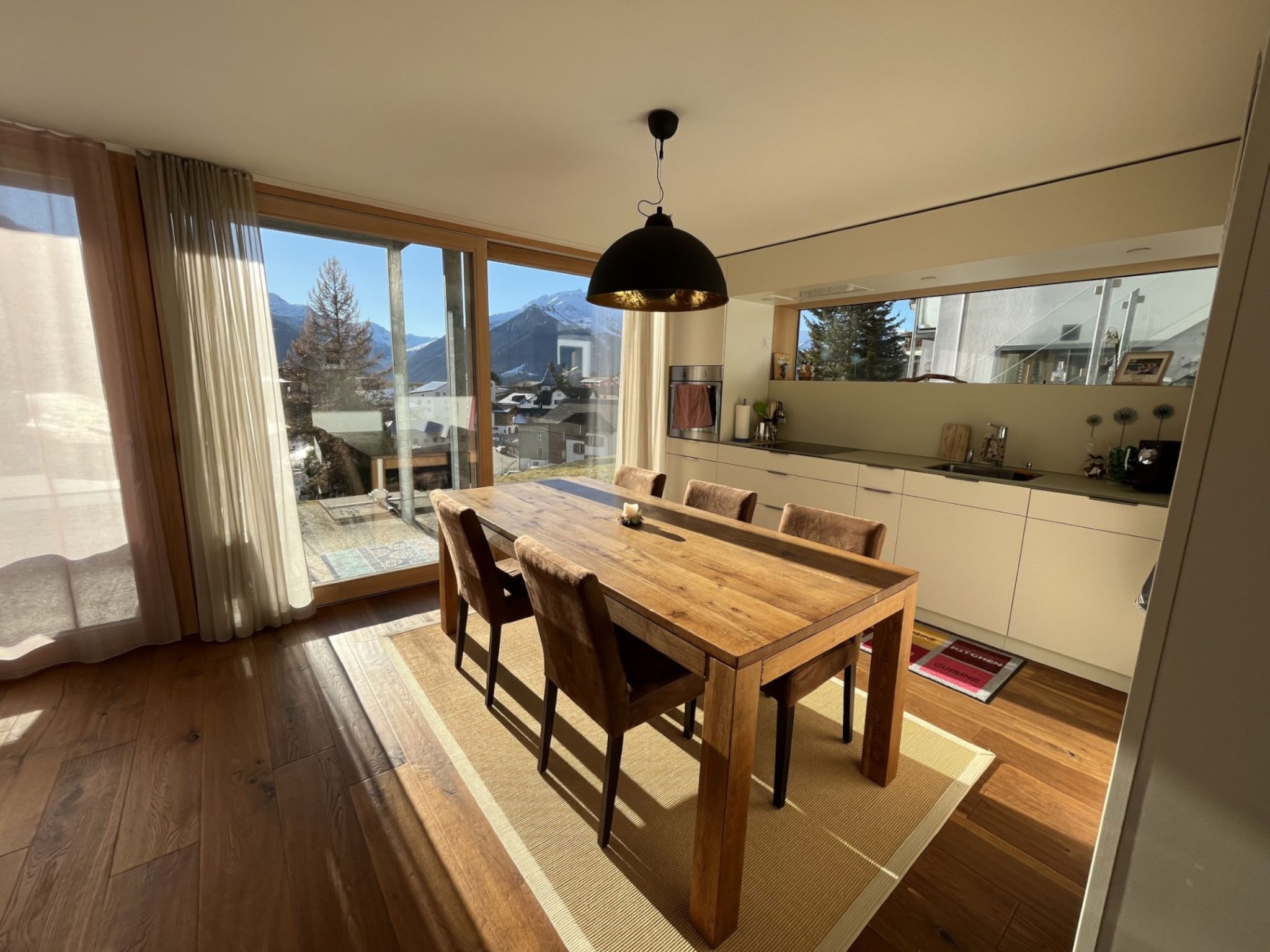 Eine moderne Küche mit Essbereich, großen Fenstern und Bergblick.