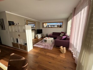 Ein stilvolles Wohnzimmer mit einem violetten Sofa, einem weißen Couchtisch und einem Holzboden.