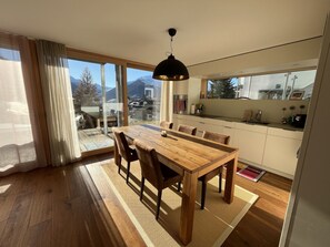 Une cuisine moderne avec un coin repas, de grandes fenêtres et une vue sur les montagnes.