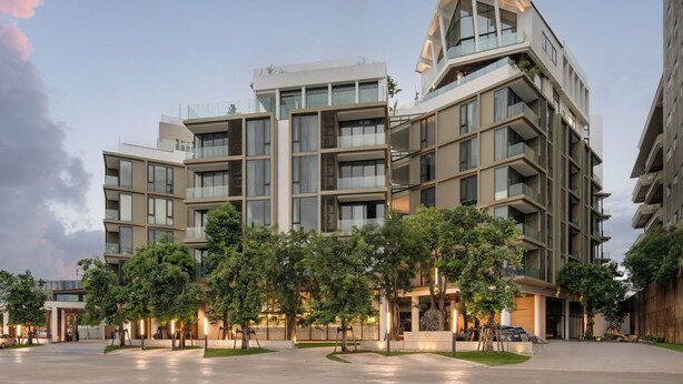 Un hotel moderno de varios pisos con techo plano, ventanas amplias y un patio ajardinado.