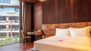 Habitación de hotel con una cama grande, un escritorio y vistas a un edificio.