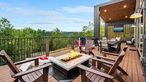 Eine Terrassenausstattung mit Feuerstelle, Sitzgelegenheiten und einem Fernsehbildschirm.