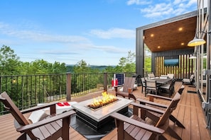 An outdoor deck with a fire pit, seating, and a TV screen. - Views/HotTub/GameRoom/2FirePits/3Masters/Sleeps10! (Sevierville)
