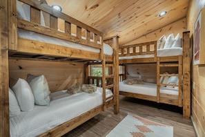 A wooden cabin with bunk beds, a ladder, and a view of greenery outside. - Views/HotTub/GameRoom/2FirePits/3Masters/Sleeps10! (Sevierville)