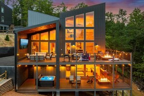 A modern multi-story building with a balcony, outdoor seating, and a hot tub. - Views/HotTub/GameRoom/2FirePits/3Masters/Sleeps10! (Sevierville)