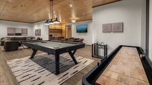 Ein stilvolles Wohnzimmer mit Billardtisch, Billardzubehör und einem Tischtennis-Tisch.