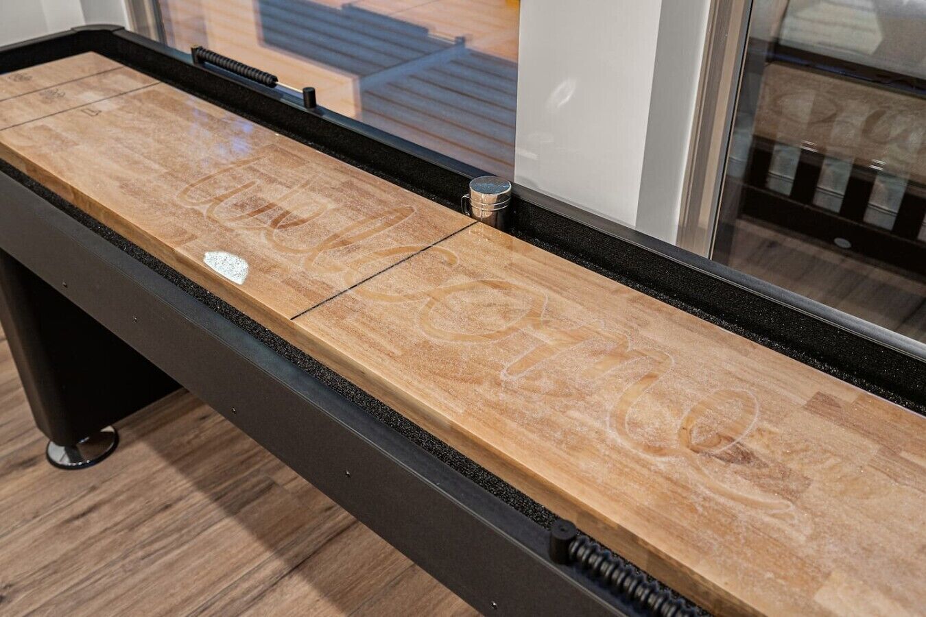 Een houten tafel met een zwarte rand en een metalen veermechanisme.