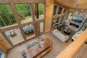 A spacious living area with a large wooden dining table, a fireplace, and a sofa. - Views/HotTub/GameRoom/2FirePits/3Masters/Sleeps10! (Sevierville)