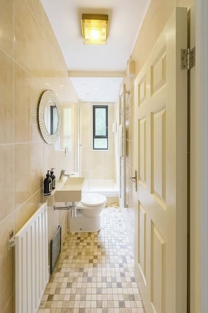 Et moderne badeværelse med toilet, håndvask og spejl.