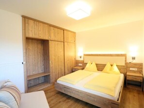 A bedroom with a wooden bed, a wardrobe, bedside tables, and a headboard with lights. - mit Terrasse by Interhome (La Villa/Stern)