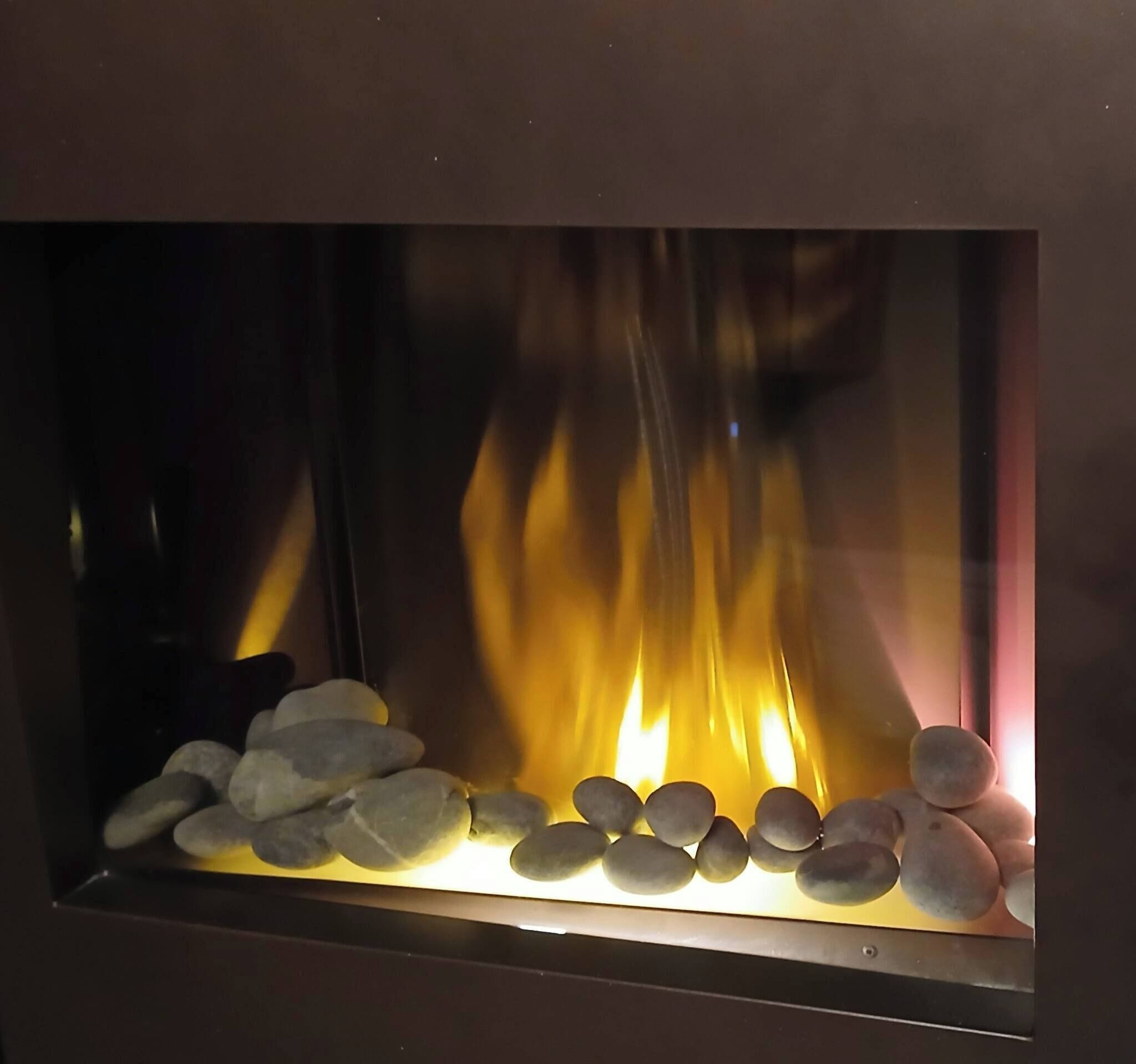 Una chimenea con una hilera de piedras lisas y fuego visible.