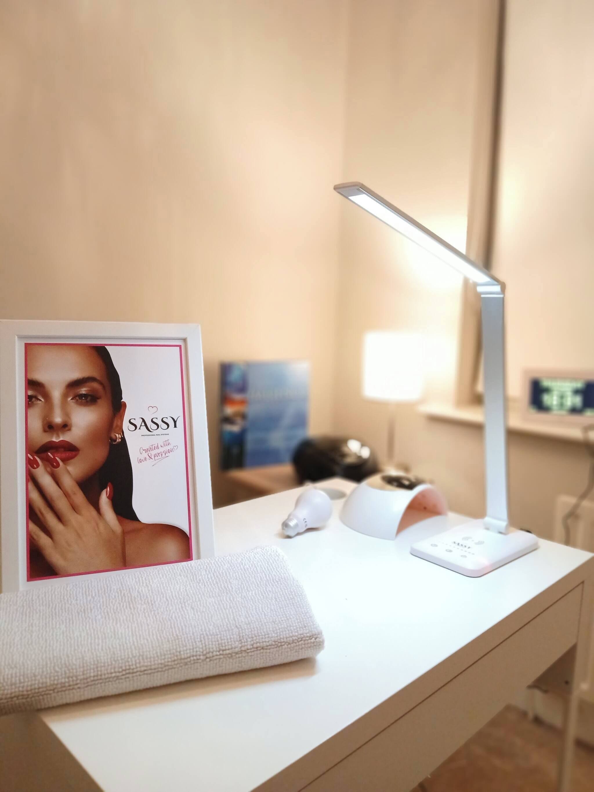Un tocador bien iluminado con espejo, una revista enmarcada, una toalla y una lámpara.
