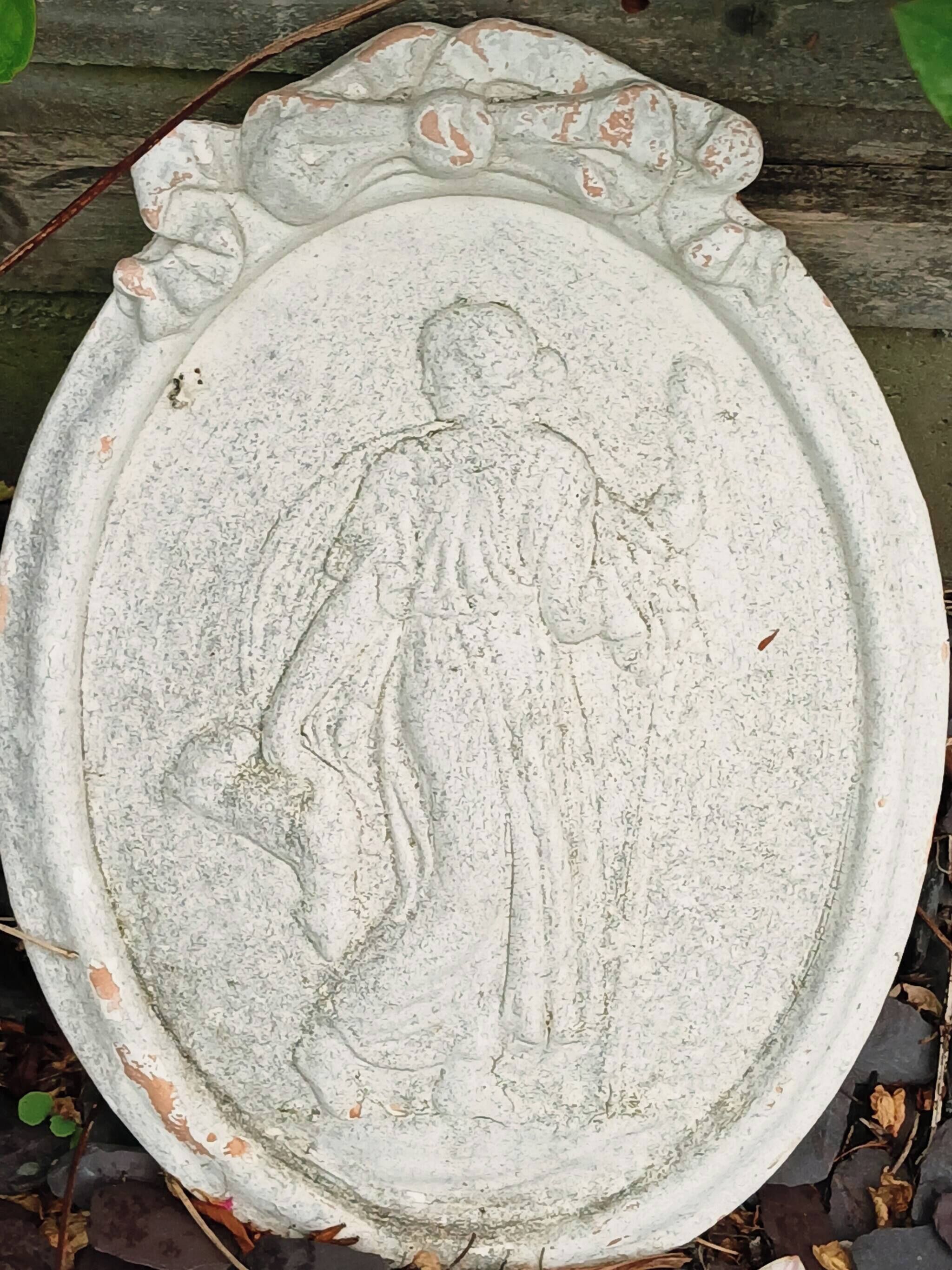 Un cuenco de piedra con una figura tallada, rodeado por un sencillo marco de madera rústica.