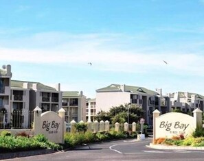 A residential complex with multiple buildings, a gated entrance, and signage indicating the name 'Big Bay.' - Private Room Near the Beach (Cape Town)