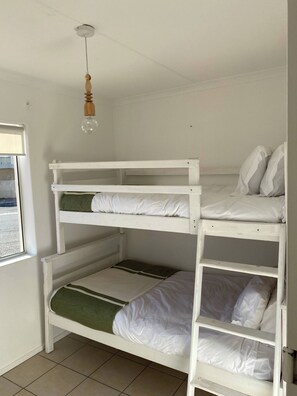 A bunk bed with three levels, a hanging light fixture, and a window with a view. - Private Room Near the Beach (Cape Town)